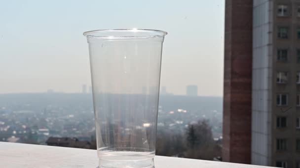 Le soda est versé dans un verre plastique transparent sur le fond de la fenêtre. Préparation d'une boisson rafraîchissante par une chaude journée d'été. — Video