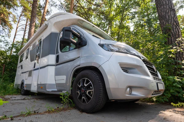 A white mobile home is parked in the woods. Caravan for life and family road travel. No people.