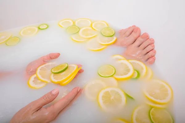 얼굴없는 아름다운 젊은 여자가 우유 레몬과 석회로 목욕을 한다. 스냅 된 사진. 피부를 하얗게 하는 목욕중 여성의 손과 발을 클로즈업 한 모습. — 스톡 사진