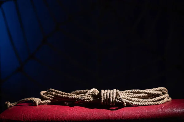 Espinho de corda para jogos de interpretação de papéis em um sofá de couro vermelho. Conceito BDSM. Um laço para a arte japonesa de shibari. Não há pessoas . — Fotografia de Stock