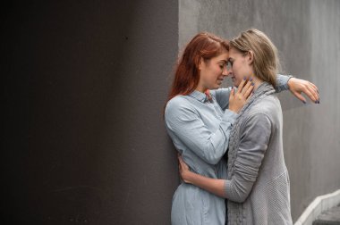 Tutkulu bir lezbiyen çift. Gri bir duvarın karşısında şefkatle sarılan iki güzel genç kadın. LGBT komünü. Kızlar randevuda..