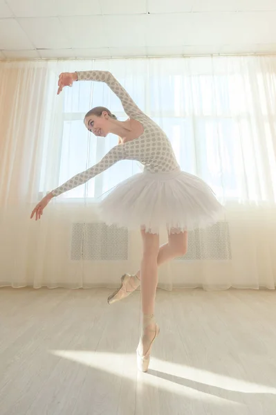 Hermosa bailarina elegante está practicando en el pasillo sobre el fondo de una ventana. Mujer delgada en tutú y zapatos puntiagudos en una clase de baile. —  Fotos de Stock