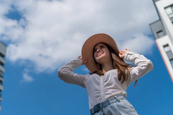 Retrato de una hermosa mujer caucásica al aire libre sobre un fondo azul del cielo. Una chica con sombrero y pantalones cortos en un caluroso día de verano. —  Fotos de Stock