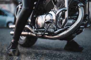 Deri taytlı bir kadın motosiklette oturuyor. Bisikletli kadın bacaklarına yakın.