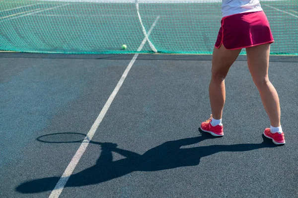 Stín ženské tenistky. Detailní záběr ženských nohou na venkovním tenisovém kurtu. — Stock fotografie