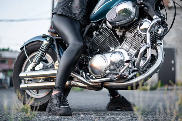 Deri taytlı bir kadın motosiklette oturuyor. Bisikletli kadın bacaklarına yakın. — Stok fotoğraf
