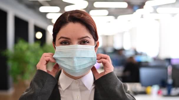 Una trabajadora de oficina feliz con un traje se quita la máscara médica y respira libremente con el pecho lleno. Una mujer sonriente quita la protección del virus. Fin de la cuarentena. Victoria sobre el coronavirus. — Vídeo de stock