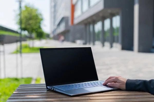 Close-up of female hands on laptop keyboard outdoors. Woman remotely works while sitting outside. — Stock Photo, Image