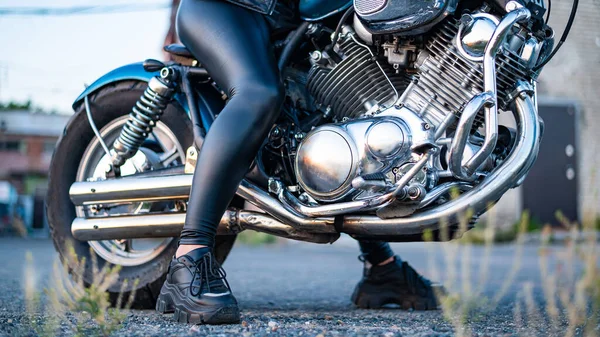 Uma mulher em perneiras de couro está sentada em uma motocicleta. perto uo de pernas femininas em uma bicicleta — Fotografia de Stock