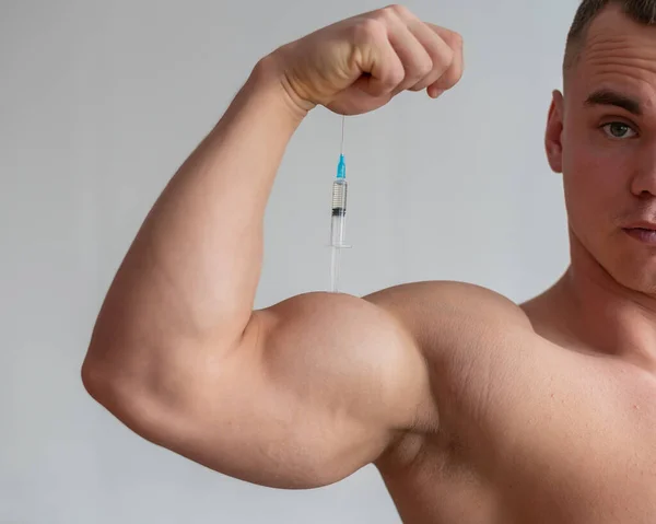 Bodybuilder masculin musculaire avec un torse nu tient une seringue de drogue. L'athlète se met une injection d'hormone de croissance. Anabolisants interdits. — Photo