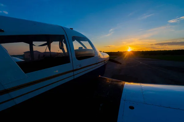 Primer plano de un pequeño avión estacionado con una hélice sobre el telón de fondo de una puesta de sol. — Foto de Stock