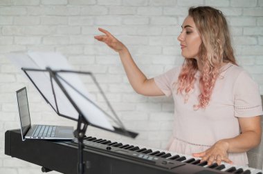 Uzaktan müzik dersleri. Şarkı söyleyen bir öğretmen dersi web kamerasına kaydediyor..