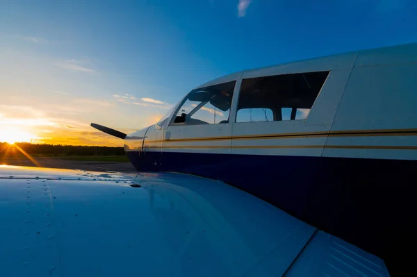 Primer plano de un pequeño avión estacionado con una hélice sobre el telón de fondo de una puesta de sol. — Foto de Stock