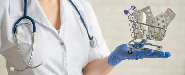 Un médecin sans visage avec un manteau médical et un stéthoscope tient un petit panier rempli de médicaments. Concept de pharmacie. — Photo