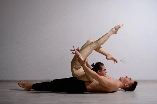 Pareja acrobática realizar el número sobre un fondo blanco. Un dúo de gimnastas ensayando una actuación con apoyo. Un hombre y una mujer muy flexible están bailando. —  Fotos de Stock