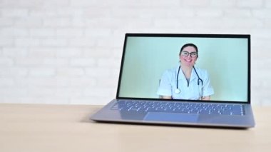 Evde teslimatı olan online eczane. Doktor eczacı dizüstü bilgisayarda video danışmanlığı yapıyor. Eldivenli bir el masaya ilaç ve haplarla dolu mini bir alışveriş sepeti koyar. Uzak satın alma.