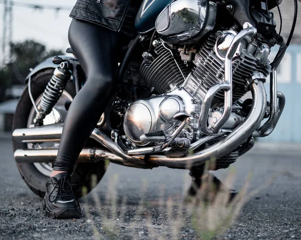 Uma mulher em perneiras de couro está sentada em uma motocicleta. perto uo de pernas femininas em uma bicicleta — Fotografia de Stock