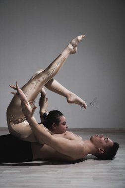 Akrobatik çift beyaz bir arkaplanda şarkı söylüyor. Bir jimnastikçi düeti bir performansı destekle prova ediyor. Bir adam ve çok esnek bir kadın dans ediyorlar..