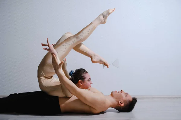 Pareja acrobática realizar el número sobre un fondo blanco. Un dúo de gimnastas ensayando una actuación con apoyo. Un hombre y una mujer muy flexible están bailando. —  Fotos de Stock