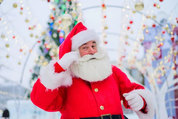 Портрет літнього чоловіка, одягненого як Санта Клаус на фоні ялинки на відкритому повітрі . — стокове фото