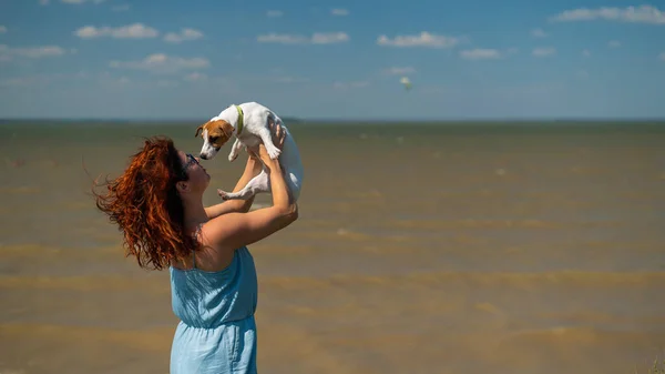 Счастливая женщина обнимается с собакой у моря — стоковое фото