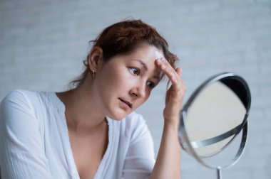 Aynada Vitiligo 'su olan beyaz bir kadının portresi.