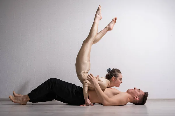 Pareja acrobática realizar el número sobre un fondo blanco. Un dúo de gimnastas ensayando una actuación con apoyo. Un hombre y una mujer muy flexible están bailando. —  Fotos de Stock
