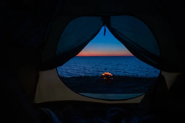 Utsikt från ett turisttält på brasan på stranden vid solnedgången. — Stockfoto