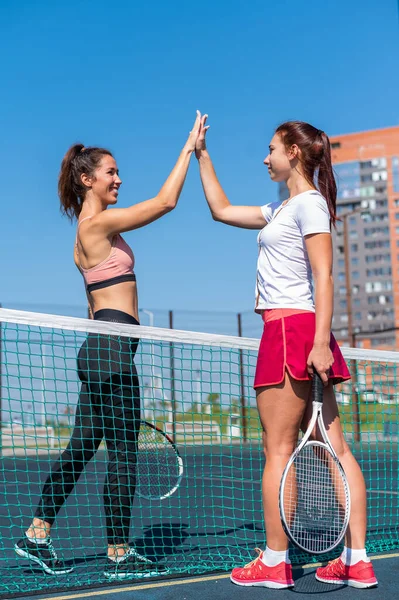两名白人女子在室外场地的网球赛前穿着运动服打招呼。3.赛前选手们给高分5分. — 图库照片