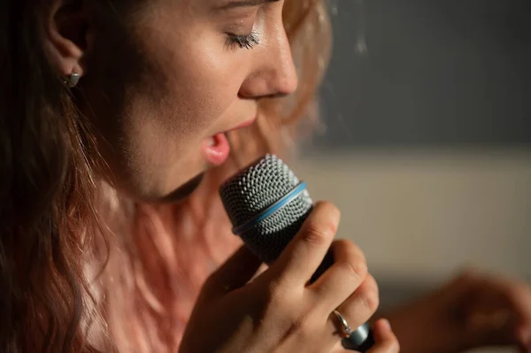 Gros plan d'une femme chantant dans un micro. — Photo