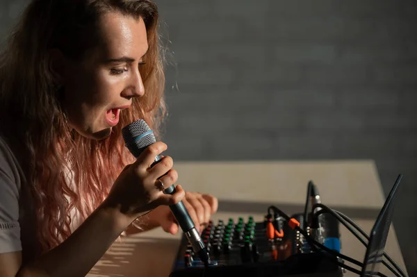 Eine Frau singt ein Lied in ein Mikrofon und nimmt ihren Gesang auf. — Stockfoto