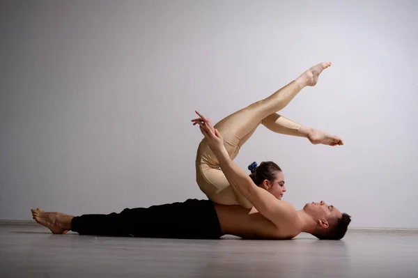 Un duo d'acrobates montrant un tour de paire. Une femme en salopette de gymnastique dans un stand de main sur un homme torse nu se trouve sur le dos. Artistes de cirque très flexibles. — Photo