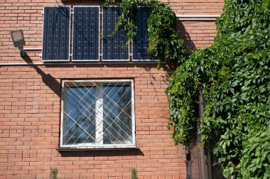 Close-up of solar panels on a red brick wall. Alternative energy source. Caring for the environment. clipart