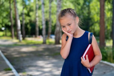 Okuldan dönerken elinde kitap tutan üzgün kız..