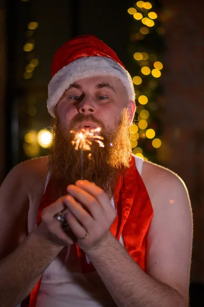 Santa con destellos de Navidad en vacaciones. Un hombre con barba roja en un sombrero de Papá Noel está celebrando el Año Nuevo. Felicidad en Navidad. —  Fotos de Stock