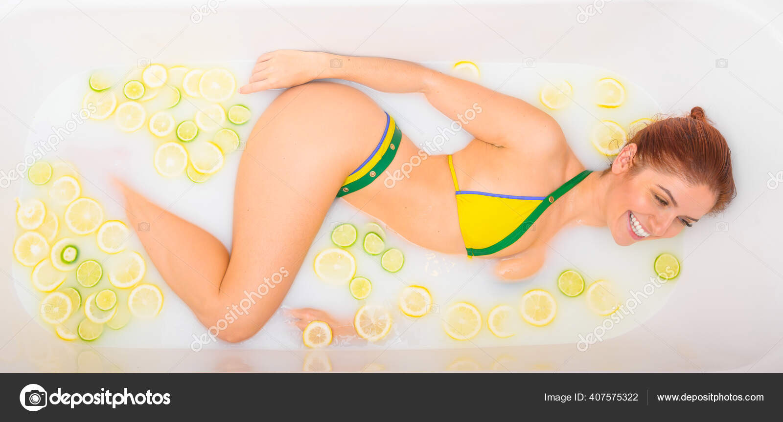 Beautiful redhead woman takes a milk bath with lemon and lime slices. Skin care and whitening