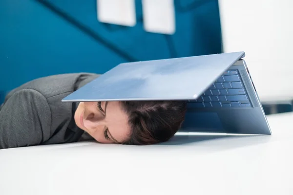 Mujer de negocios agotado cubierto la cabeza con el ordenador portátil. Trabajadora cansada con una computadora sobre su cabeza. — Foto de Stock