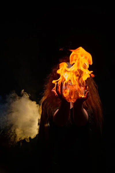 Uma bruxa ruiva malvada segura fogo em suas mãos. — Fotografia de Stock