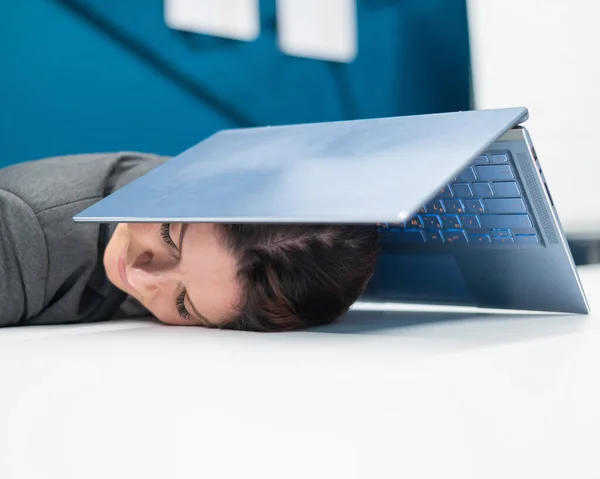 Utslitt forretningskvinne dekket hodet med laptop. Trøtt kvinnelig arbeider med datamaskin over hodet. – stockfoto