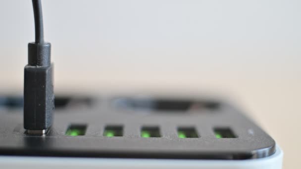 Modern convenient multi-port usb charger for devices. Close-up of a female hand plugging multi-colored cables into a power outlet. Macro. — Stock Video