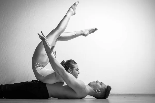 Pesada pose de circo. Un joven sostiene a una mujer flexible. Dos acróbatas o bailarines posando sobre un fondo blanco. Un par de gimnastas realizan arte. —  Fotos de Stock