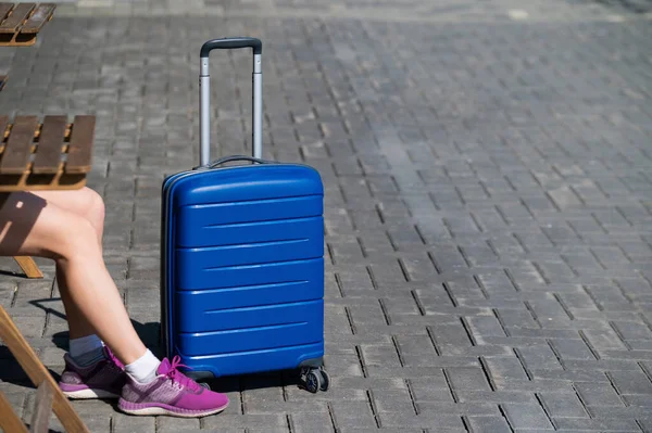 Vrouwelijke benen met sneakers en een blauwe koffer buiten. — Stockfoto