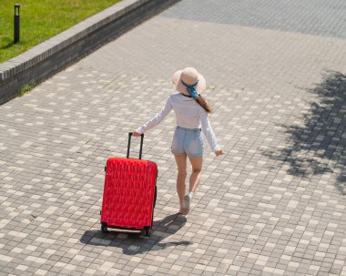 Beyaz bir kadın kırmızı bir bavulla sokakta yürüyordu..