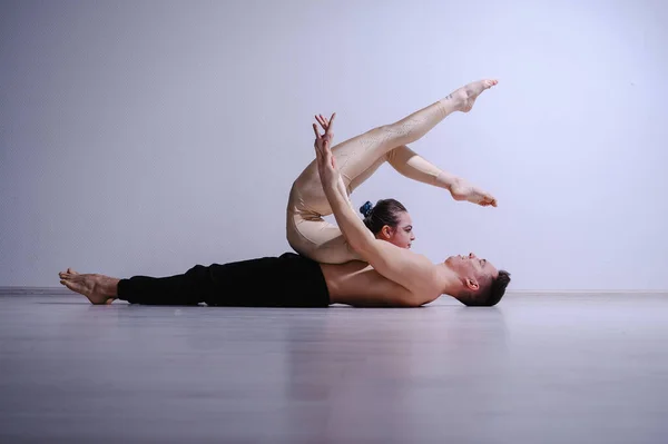 Pareja acrobática realizar el número sobre un fondo blanco. Un dúo de gimnastas ensayando una actuación con apoyo. Un hombre y una mujer muy flexible están bailando. —  Fotos de Stock