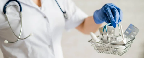 Uma médica feminina sem rosto segura uma mini cesta com medicamentos — Fotografia de Stock