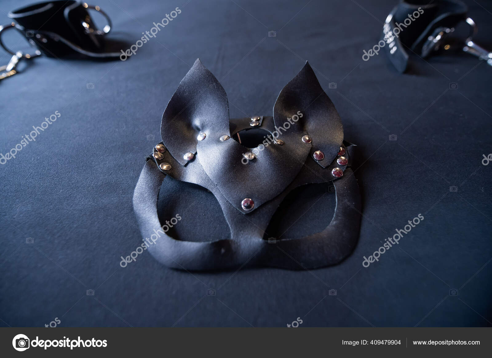 Role-play mask and leather handcuffs on a black sheet. BDSM equipment. —  Stock Photo © inside-studio #409479904