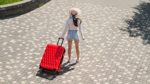 Kaukasische Frau läuft mit rotem Koffer die Straße entlang. — Stockfoto