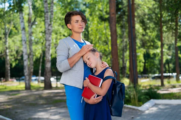 Een vrouw knuffelt een ongelukkige schoolmeisje dochter — Stockfoto