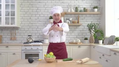 Yaşlı aşçı mutfakta poz veriyor.
