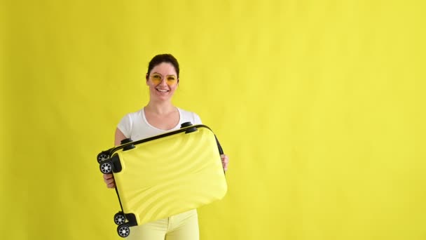 노란 배경 여행 가방을 든 흥분 한 여자 — 비디오